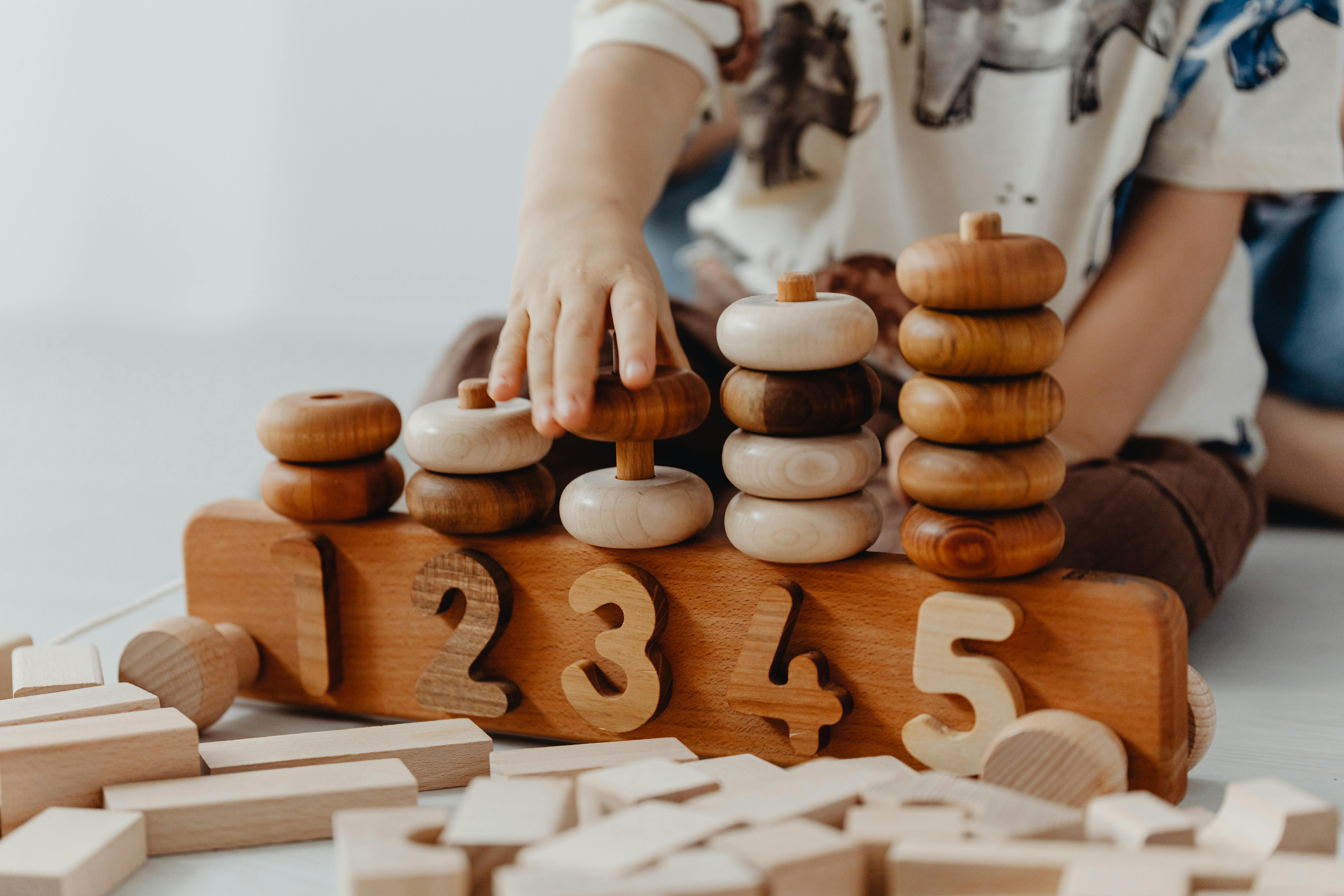 Services fiduciaires et conseils spécialisés pour la petite enfance — finidoo. Enfant jouant avec un jouet éducatif en bois, illustrant l’accompagnement fiduciaire et stratégique de finidoo pour les institutions de la petite enfance en Suisse romande.